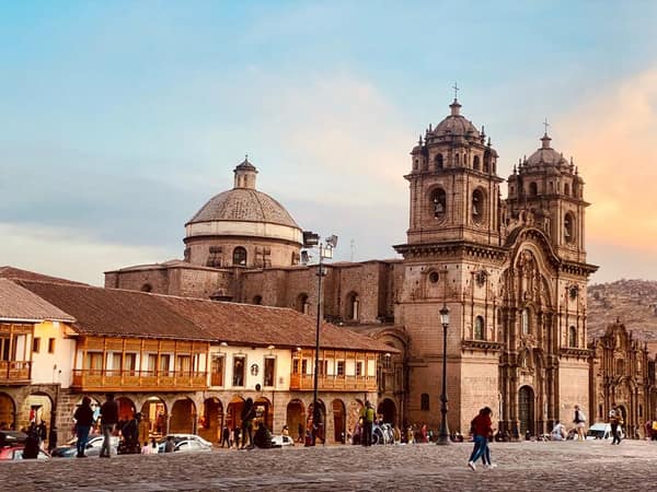 Plaza de Armas de Cusco al atardecer, piedra inca y torres coloniales iluminadas en dorado
