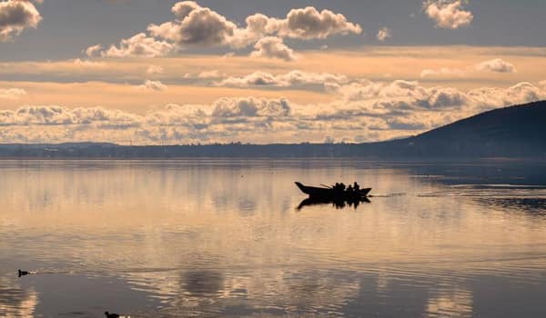 Bote de totora navegando el Lago Titicaca al atardecer